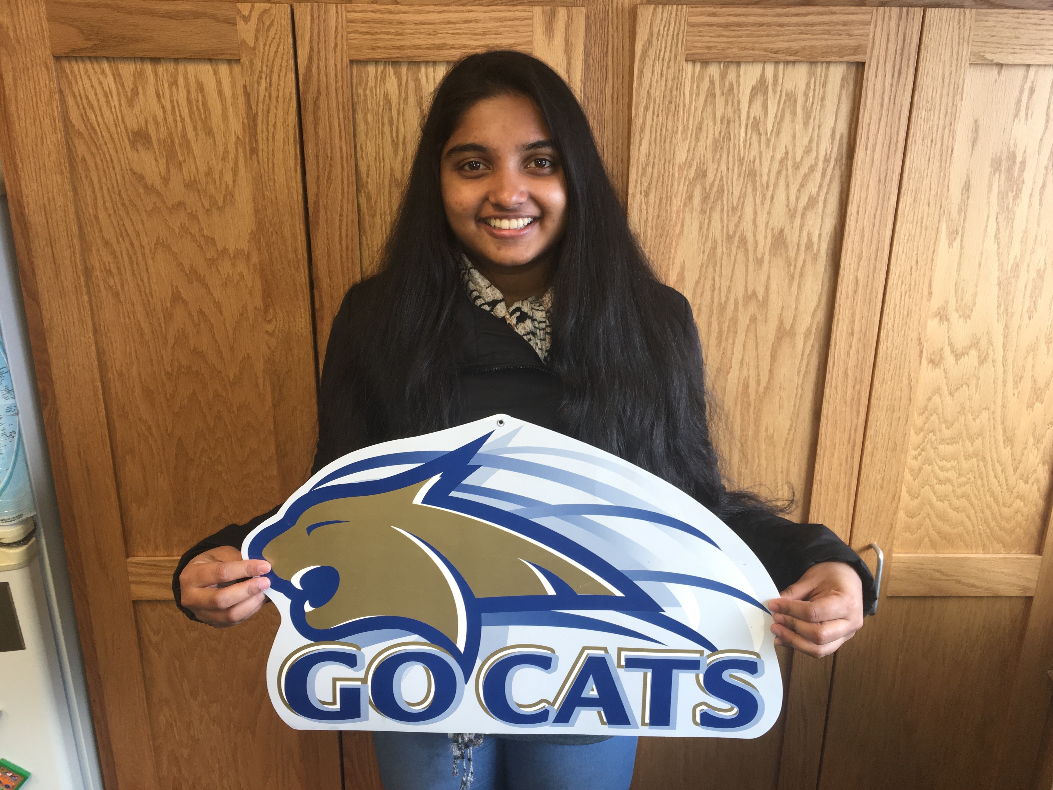 Student Ambika holding a sign that says "Go Cats" 