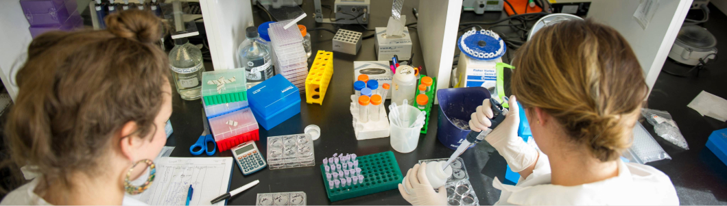 Two woman in white coats working on medicine