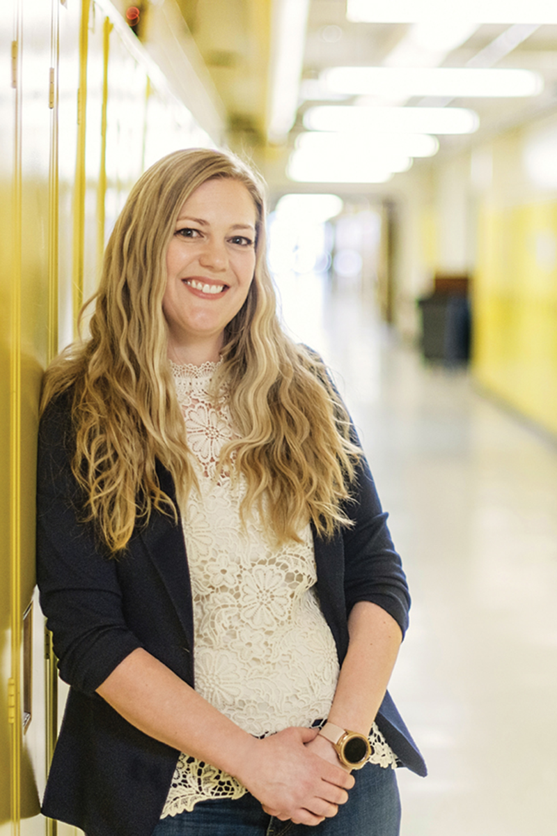 Person with blonde hair standing in a hallway of lockers