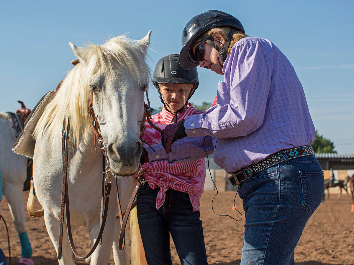 4-H member and volunteer tacking up a horse
