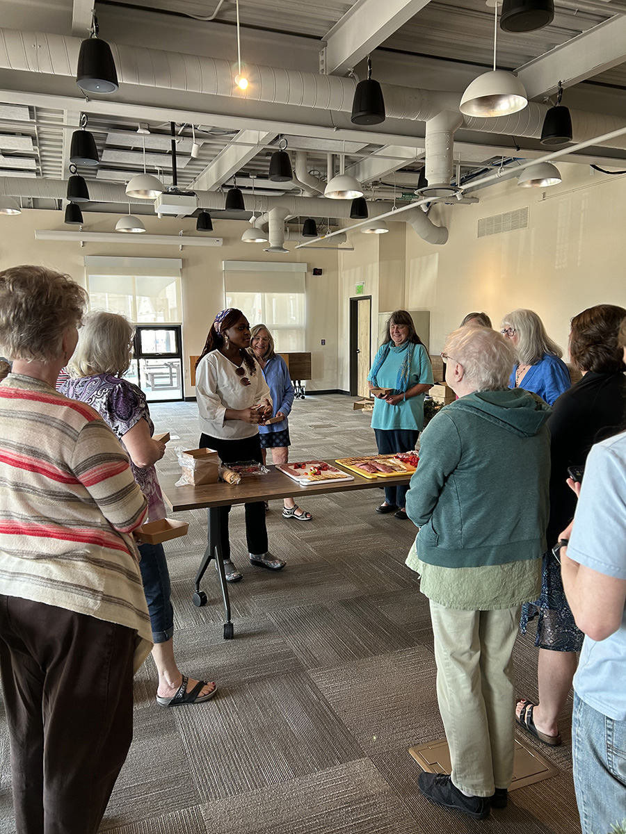 People stand at a table filled with snacks. 