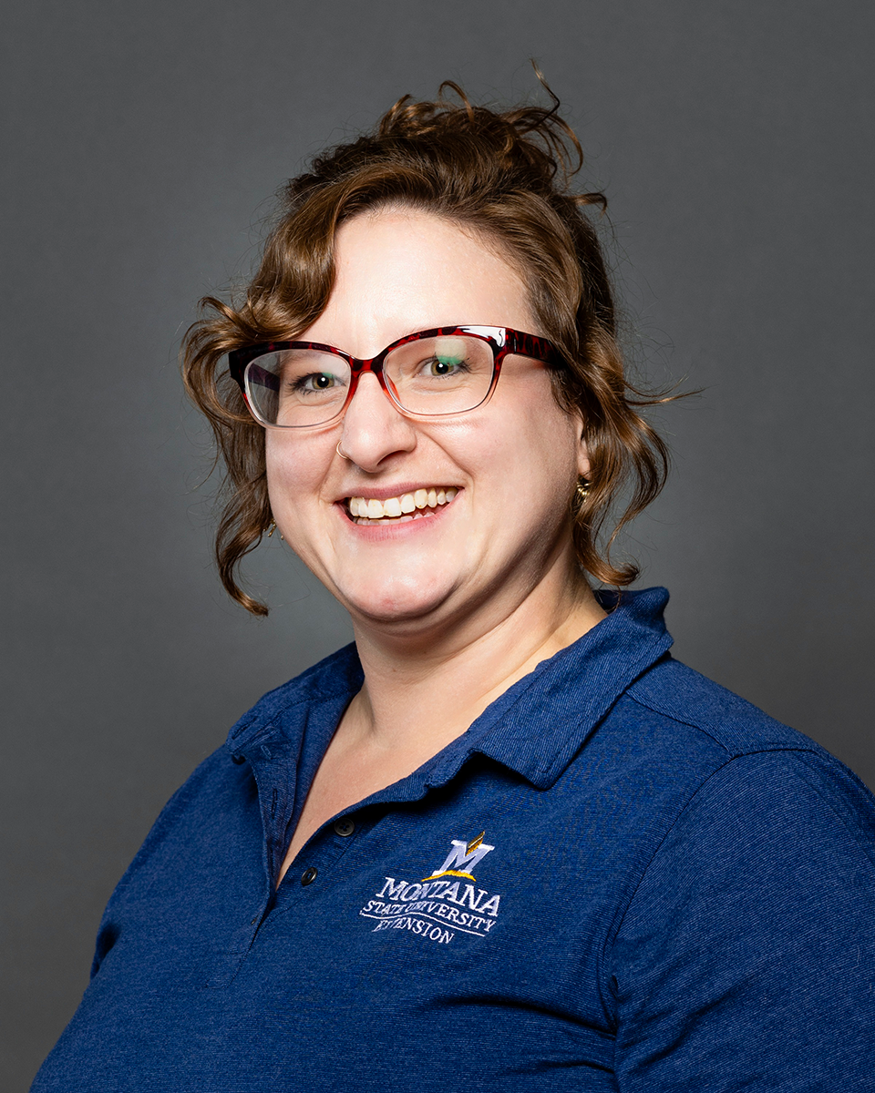 Portrait of a woman with brunette hair wearing a blue collared shirt and glasses