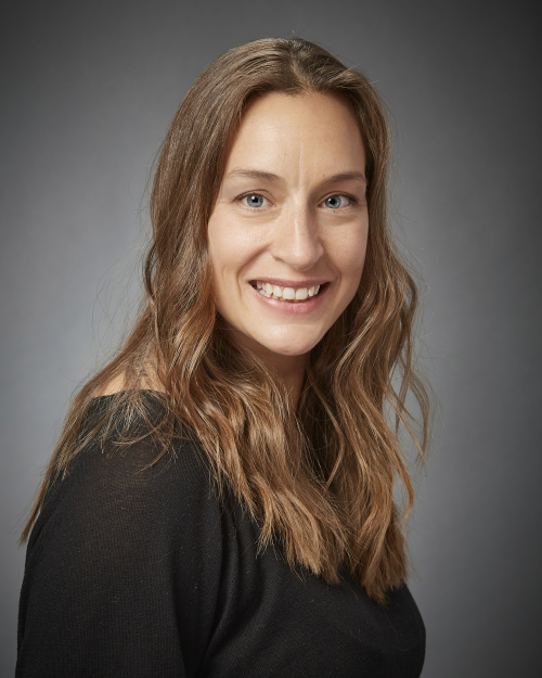 Portrait of a woman with brown hair and a black shirt smiling to the camera