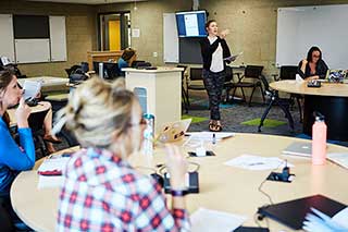Instructor in a classroom with students at group tables