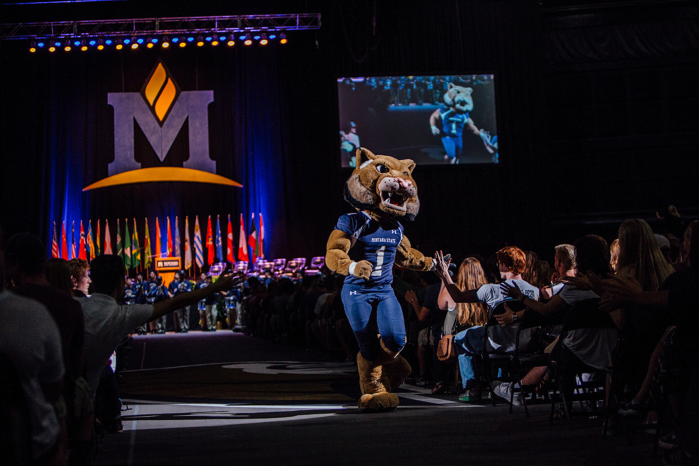 Champ wallking down the aisle of an auditorium getting high-fives