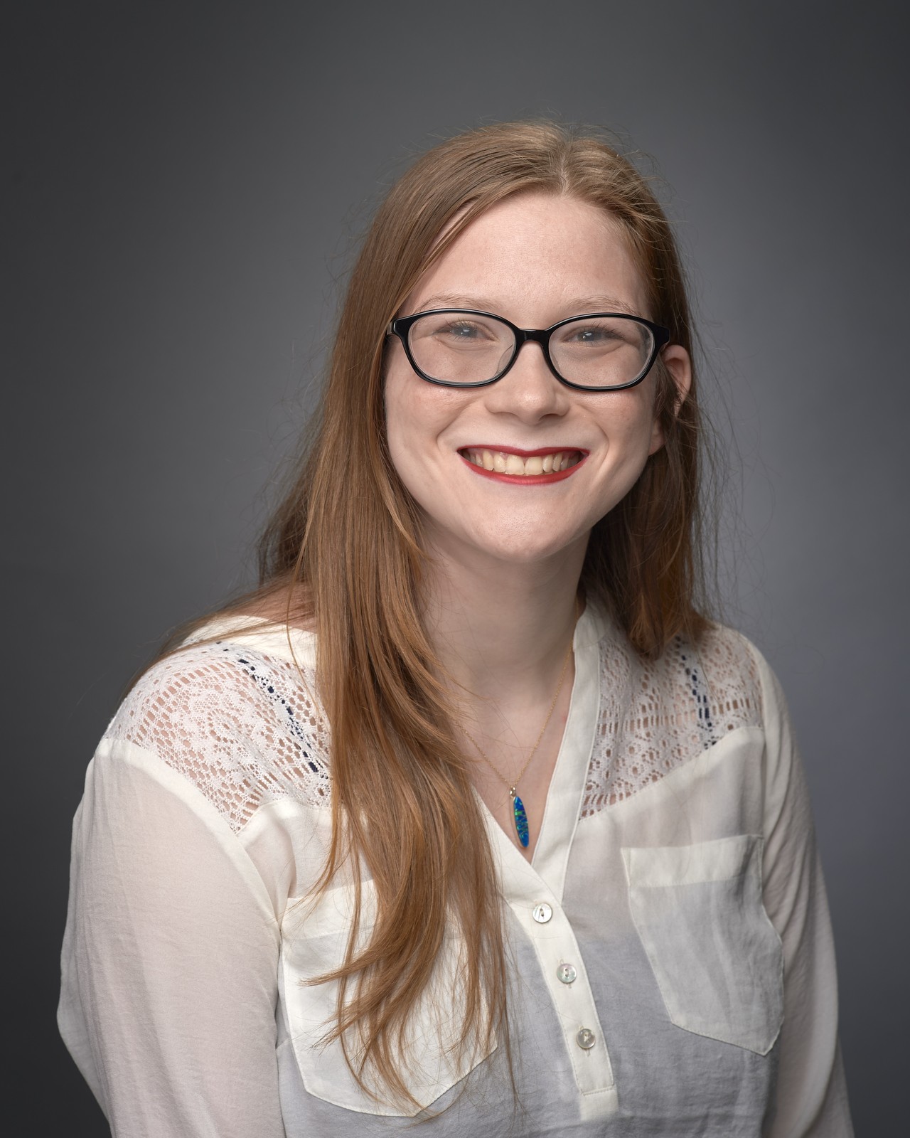 Professional portrait of a person wearing black glasses and a button up white shirt