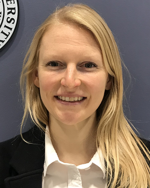 A blonde long haired person wearing a white undershirt and a black blazer