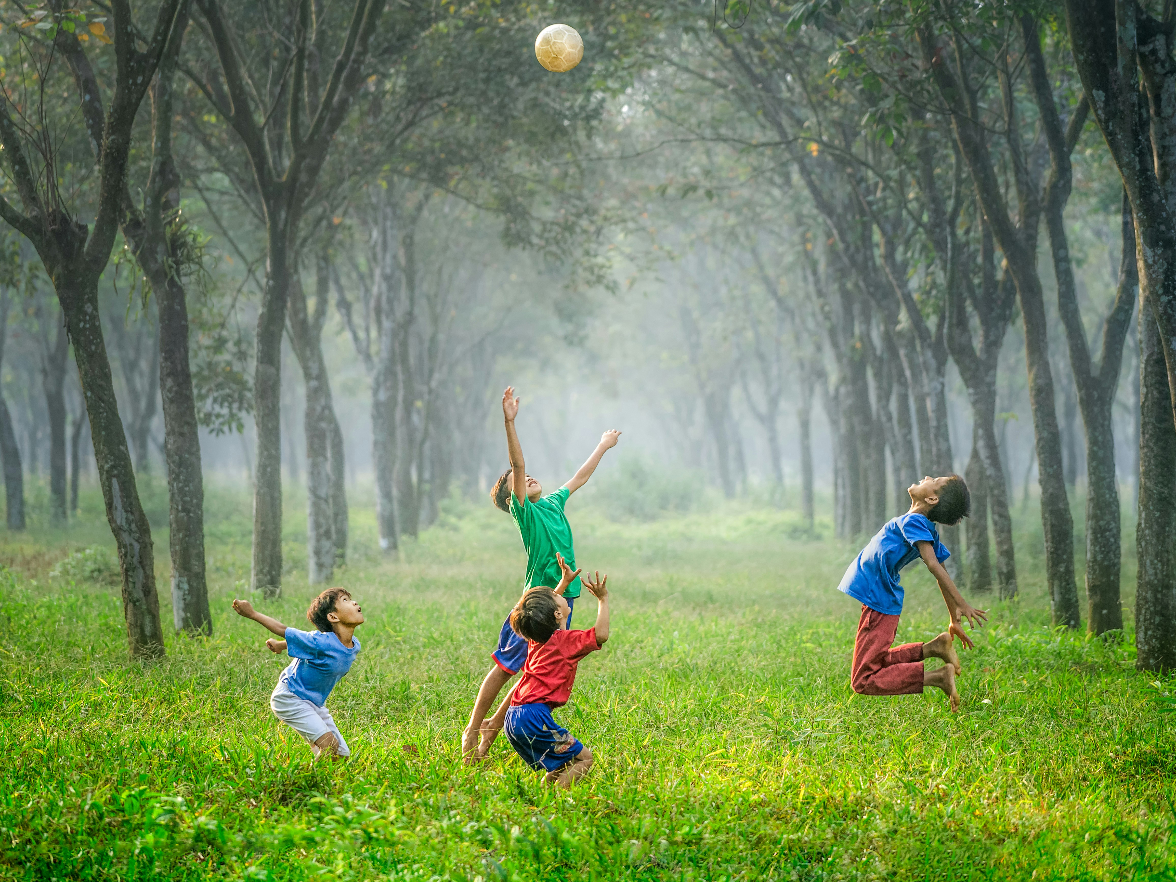 Stock image of four children playing with a soccer ball