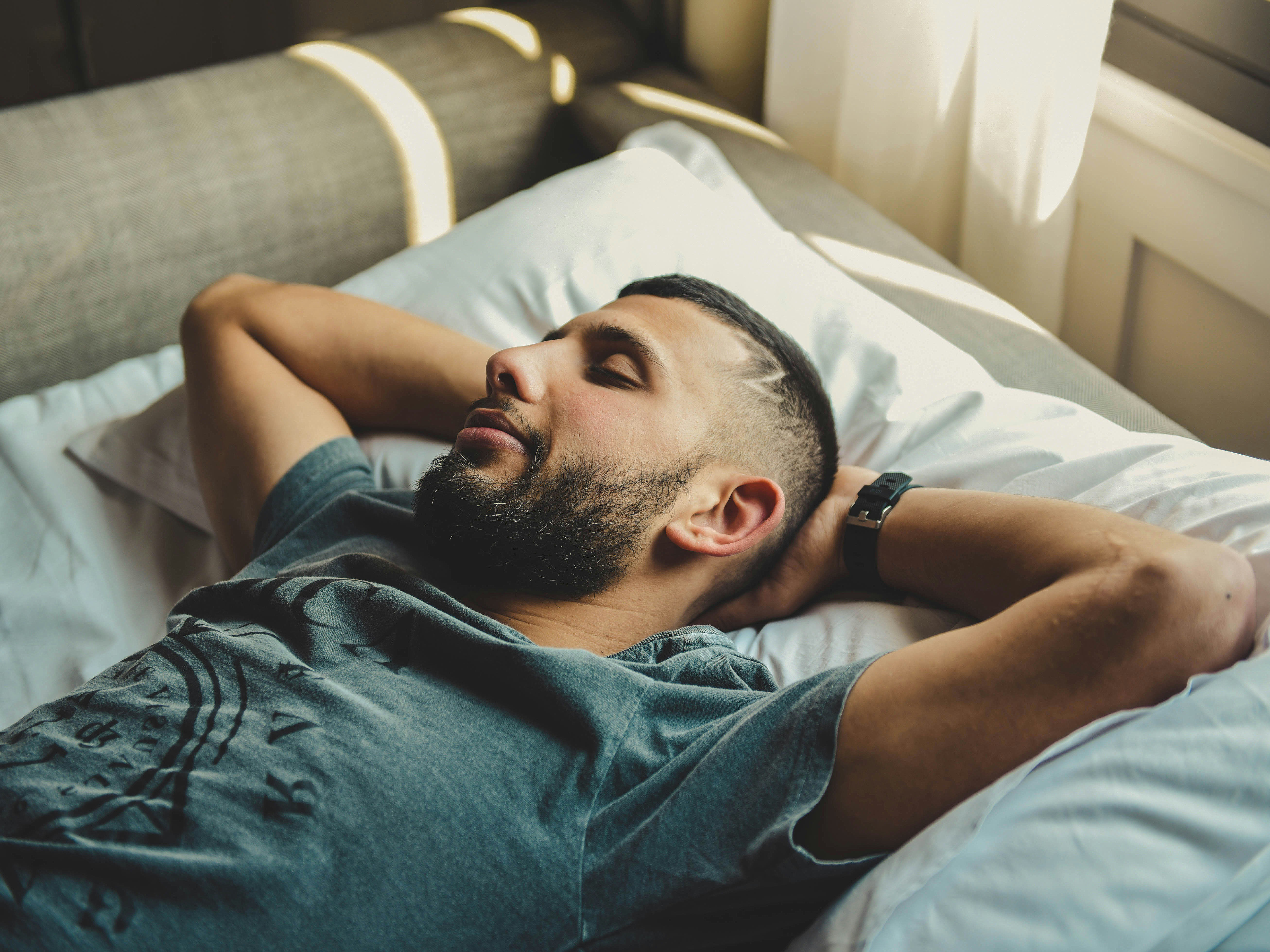 Stock image of a man sleeping with his arms behind his head