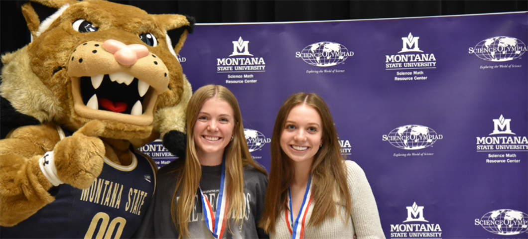 Two students posing with Champ, the MSU mascot
