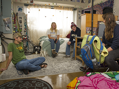 Four students hanging out in a dorm room