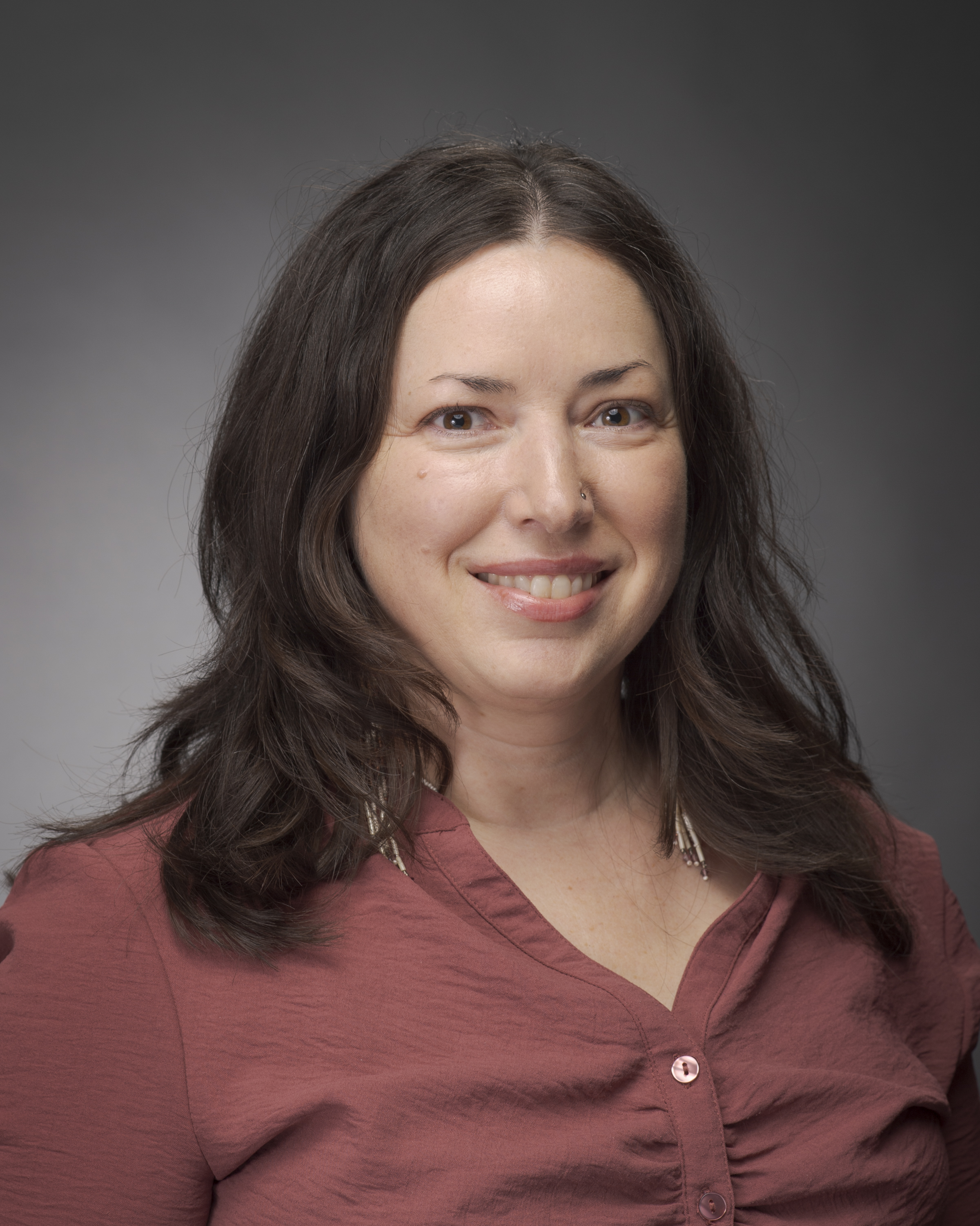Portrait of a person with long dark hair and a red shirt on