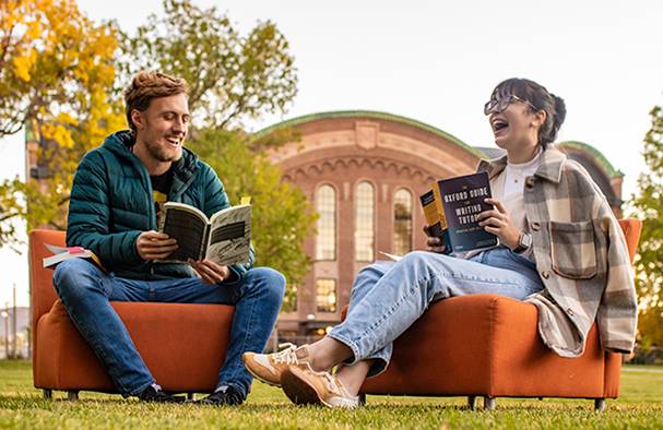 Two tutors outside reading on orange couches